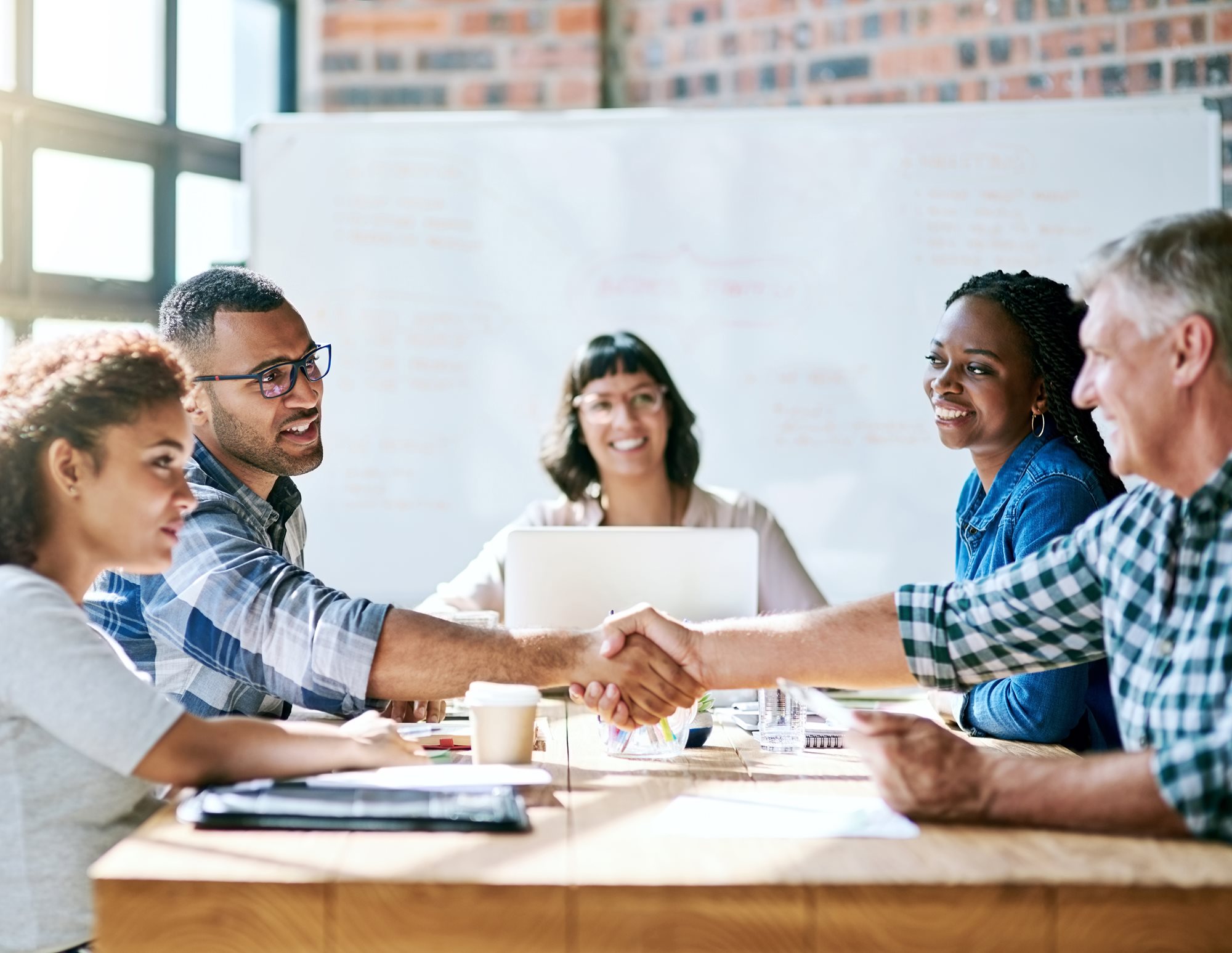 A group of colleagues happily working in a sunny room together.
